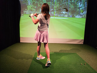 Teenage schoolgirl girl plays in a golf simulator indoors