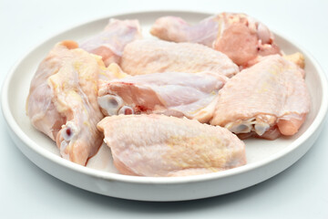 The picture shows chicken meat, wings, cut into pieces and placed on a plate.