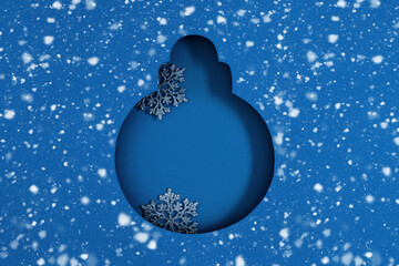 Stylish and creative Christmas background with cut out silhouette of Christmas round ball on blue paper with Christmas decorations, confetti stars. Flat lay mockup, top view