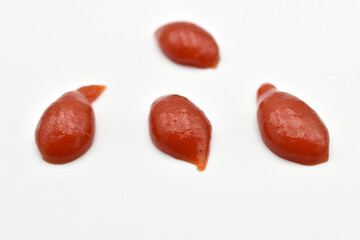 Drops of tomato chili ketchup on white surface.