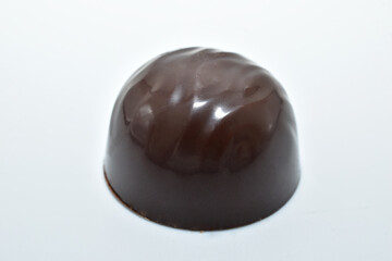 Round chocolate candy with filling on a white background.