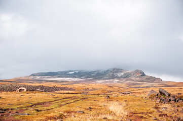 Rugged mountain landscape with golden tundra and cloudy sky