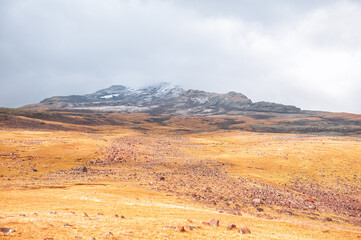 Rugged mountain landscape with golden tundra and cloudy sky