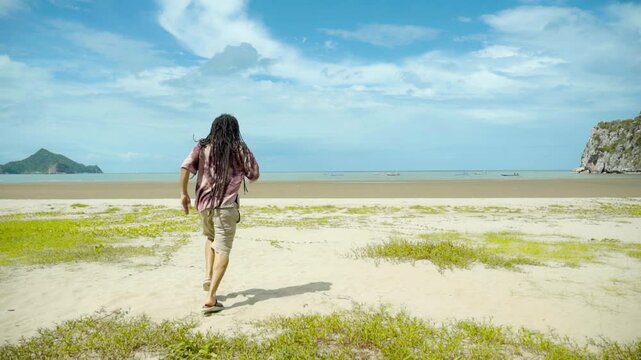 hippie rastaman dreads locks man run to the beach on a sunny day blue skies 
