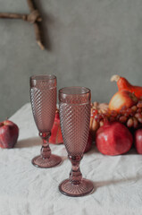 Autumn still life harvest Thanksgiving table serving with pumpkins pommegranates and grapes on linen cloth with candles modern minimalist scandinavian sustainable eco styling
