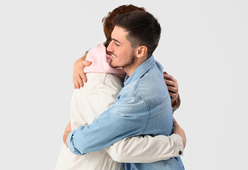 Male friends hugging on white background