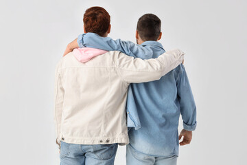 Male friends hugging on white background, back view