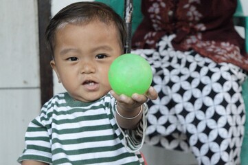 boy in green striped t-shirt smiling holding ball