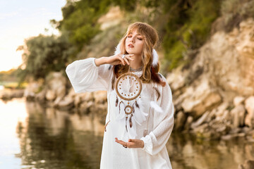 Young female shaman with dream catcher near river