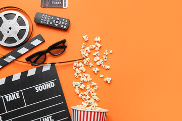 Movie clapper with film reel, cinema ticket, remote control and glasses on orange background