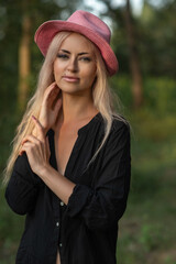 Portrait of a beautiful young blonde girl in a black shirt in the forest.