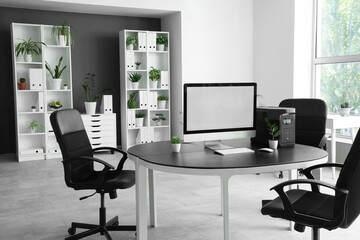 Blank computer monitor with portable power station on desk in office interior