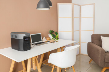 Interior of office with workplace, armchair and portable power station