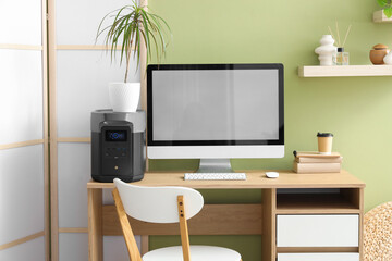 Interior of office with workplace, portable power station and folding screen