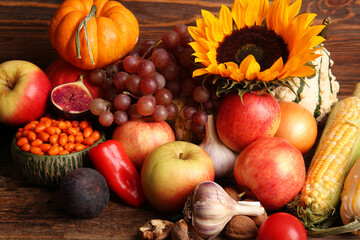 Fresh vegetables with fruits and sunflower on wooden background. Harvest festival