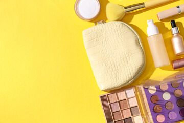 Cosmetic bag and makeup products on yellow background