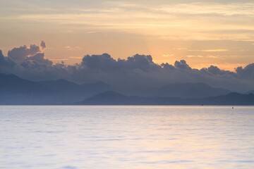 Obraz premium Serene Sunset Over Calm Waters with Distant Mountains