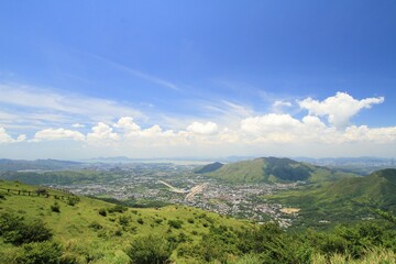 Obraz premium Scenic View of Rolling Hills and Distant Town Under Blue Sky, Tai Mo Shan, Hong Kong