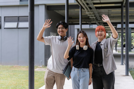 Three cheerful students waving hands while walking in a university corridor, expressing happiness and greeting