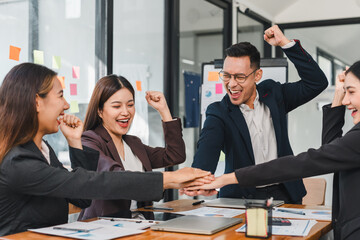 Team celebrating success in modern office, showing excitement and collaboration. Their expressions...