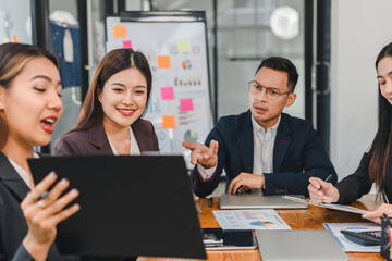 Collaborative business meeting with diverse professionals discussing strategies and analyzing data. Engaged expressions highlight teamwork and communication