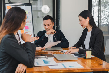 Business meeting with three professionals discussing project details, analyzing documents, and collaborating on strategies. atmosphere is focused and engaged