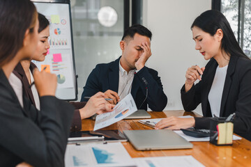 group of professionals in meeting, showing concern and frustration. man appears stressed while reviewing documents with colleagues