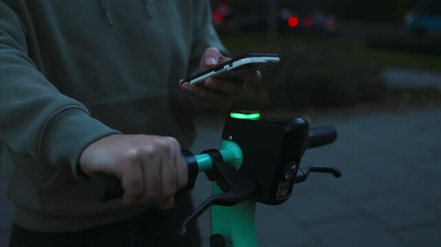 Electric scooter in the citycloseup. Active lifestyle. Urban eco friendly transport concept.Renting bike using rental app on smartphone. Using bike sharing city service. Paid rent of electric scooter.