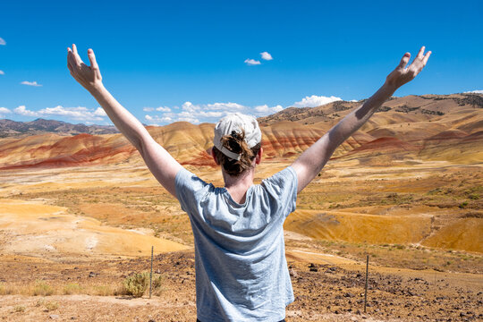 Woman celebrating the Scenic Beauty of Painted Hills desert at John Day Fossil Beds National Monument. Oregon, USA  - Powered by Adobe