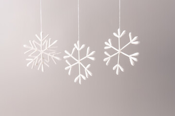 three snowflake is made from white cotton swabs, The background is plain and light-colored, a creative and simple DIY craft idea using everyday materials.