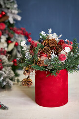 Christmas composition with pine needles in a red box on a blue background