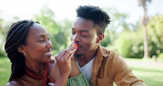 Park, black couple and happy on picnic with strawberry on date for fun, support or bonding in Kenya. People, relationship and smile or laughing at garden with fruit for care, love or trust on break