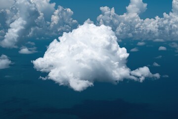Fototapeta premium A large cloud in the sky with a blue ocean in the background. The cloud is white and fluffy, and it looks like it's about to rain. The sky is clear and blue, and the ocean is calm