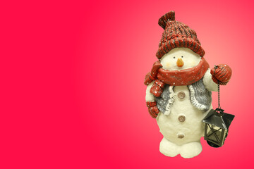 A snowman with a red hat and scarf stands in the snow