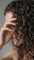 A close-up of the woman's hand running her fingers through her curly hair, using an organic shampoo product for thickening hair. generative ai