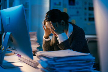 Young businesswoman is having a headache and feeling stressed while working late at night in the...