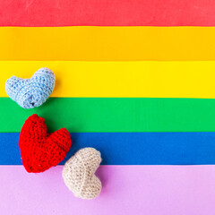 Knitted hearts on LGBTQ colors flag, top view, copy space for the text