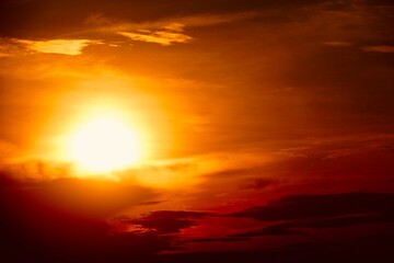 This is a beautiful sunset or sunrise photo with bright orange, yellow, and red as the main colors in the sky. The sun is partially obscured by clouds, which makes the sky look brighter and warmer.