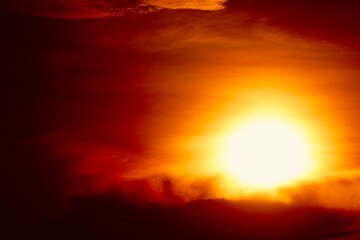 Obraz premium This is a beautiful sunset or sunrise photo with bright orange, yellow, and red as the main colors in the sky. The sun is partially obscured by clouds, which makes the sky look brighter and warmer.