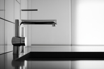 Modern chrome faucet above a sleek black kitchen sink in natural light