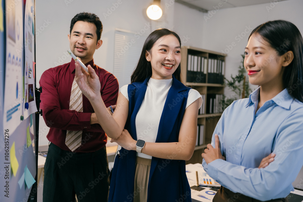 Poster three asian businesspeople are discussing strategy in front of a whiteboard during an office meeting
