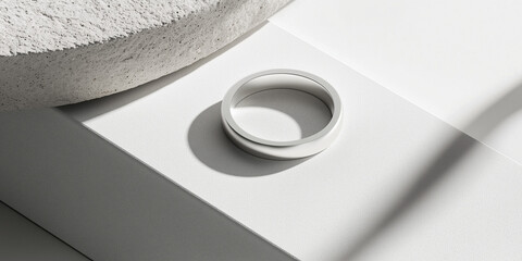 A sleek wedding band placed on the side of a matte white background, showcasing its smooth design and modern appeal