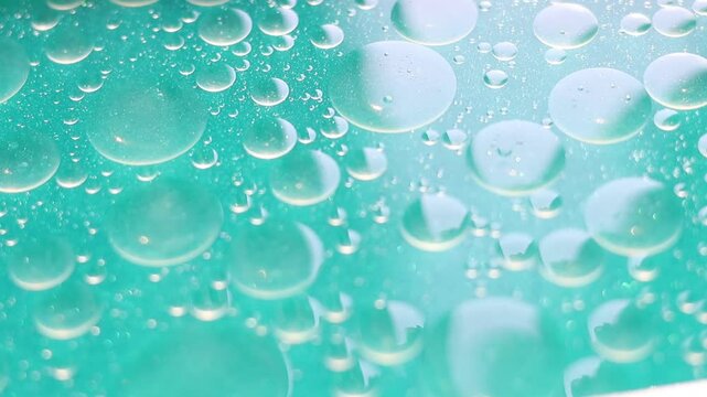 Una toma de cerca de varias burbujas de agua y aceite en movimiento en un fondo de color azul claro
