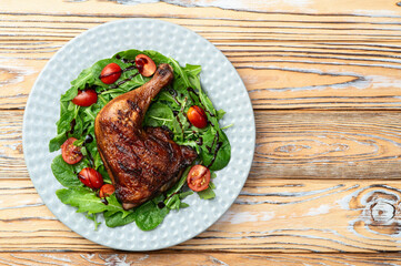 Grilled chicken legs with tomatoes and salad . Top view