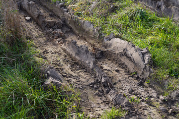Tracks in the mud. We see deep grooves in the grass.