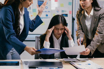 Stressed asian businesswoman suffering from headache while colleagues arguing about paperwork and...