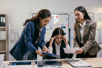 Stressed asian businesswomen having dispute over paperwork showing bad results, pointing at charts...