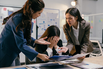 Two businesswomen are scolding a stressed colleague during an office meeting, highlighting...
