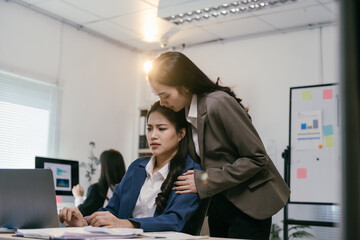 Asian businesswoman is consoling her upset colleague, placing a comforting hand on her shoulder as...
