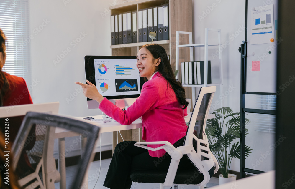 Poster young businesswoman pointing at computer screen showing positive charts and smiling during a present